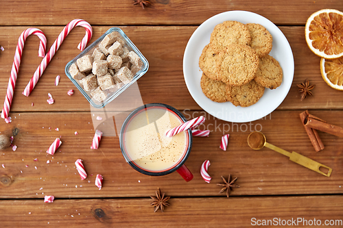 Image of cup of eggnog with candy cane, cookies and sugar