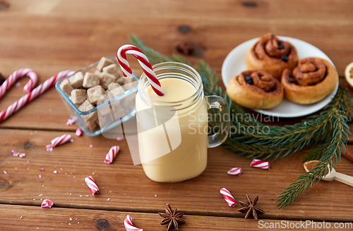 Image of eggnog with candy cane in mug and cinnamon buns