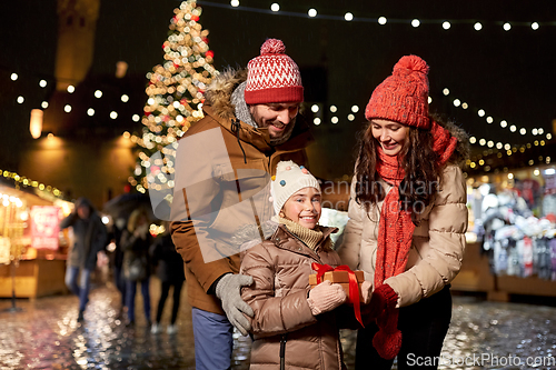 Image of happy family with gift at christmas market in city