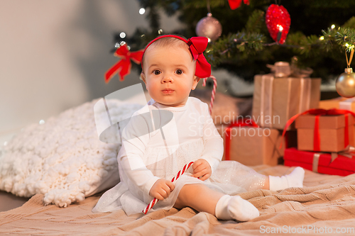 Image of baby girl at christmas tree with gifts at home