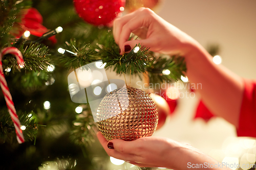 Image of hands decorating christmas tree with ball