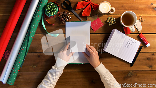 Image of hands wrapping christmas gift into paper at home