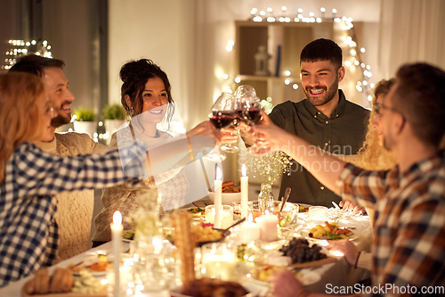 Image of happy friends drinking red wine at christmas party