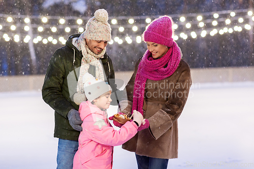 Image of happy family eating pancakes on skating rink