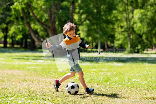 Image of happy little boy with ball playing soccer at park