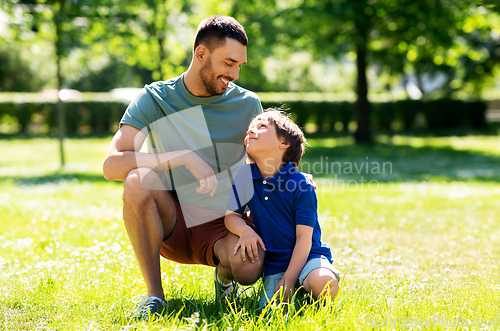 Image of happy father and son talking at summer park