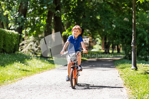 Image of happy little boy riding bicycle at summer park