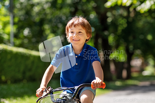 Image of happy little boy riding bicycle at summer park