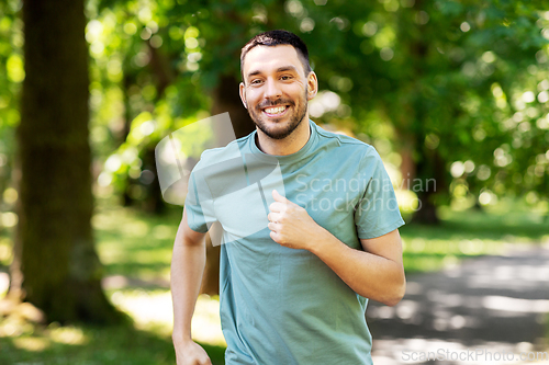Image of happy young man running at summer park