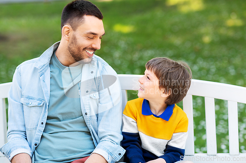 Image of father with son sitting on park bench and talking