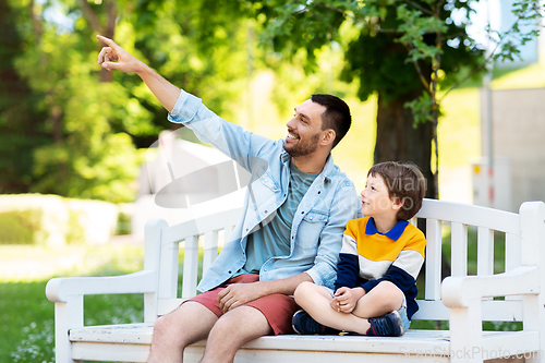 Image of father showing something to son sitting on bench