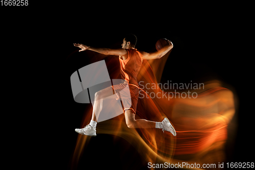 Image of Young arabian basketball player of team in action, motion isolated on black background in mixed light. Concept of sport, movement, energy and dynamic.