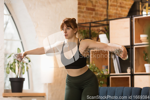 Image of Young woman exercising fitness, aerobic, yoga at home, sporty lifestyle. Getting active during lockdown, quarantine. Home gym.
