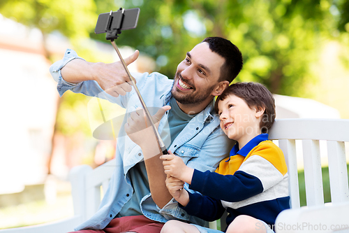 Image of father and son taking selfie with phone at park