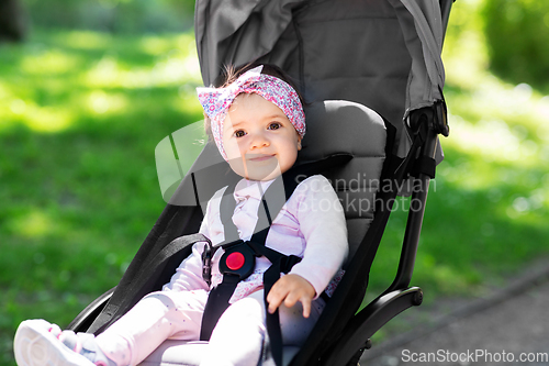 Image of happy baby girl sitting in stroller at summer park