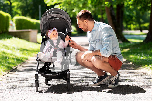 Image of happy father with child in stroller at summer park