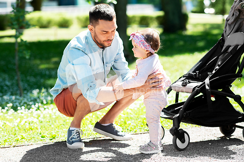 Image of happy father with child in stroller at summer park