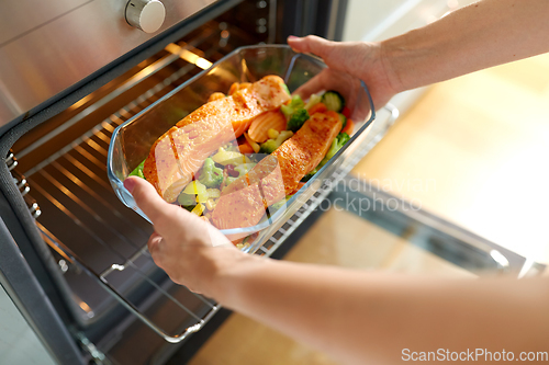 Image of woman cooking food in oven at home kitchen