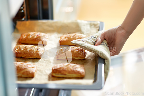 Image of woman cooking food in oven at home kitchen