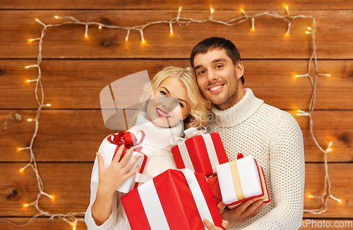 Image of happy couple in sweaters with christmas gifts