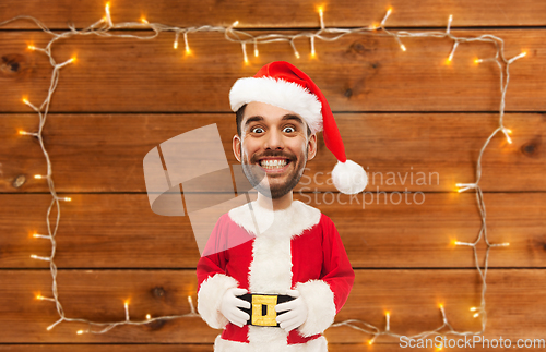 Image of happy santa over garland on wooden background