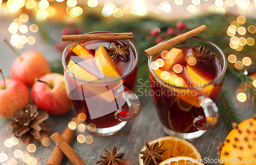 Image of glass of hot mulled wine, cookies, apples and fir