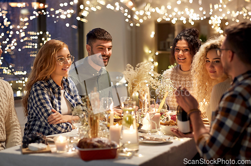 Image of happy friends with red wine at christmas party