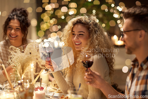 Image of happy friends drinking red wine at christmas party