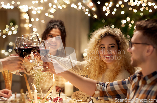 Image of happy friends drinking red wine at christmas party