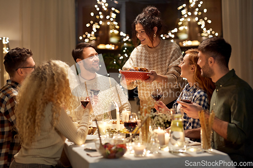 Image of happy friends having christmas dinner at home