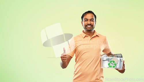 Image of smiling young indian man sorting metallic waste