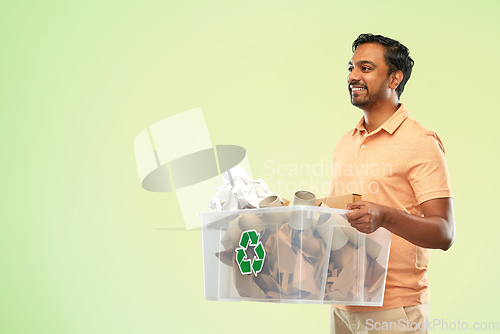 Image of smiling young indian man sorting paper waste