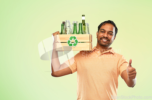 Image of smiling young indian man sorting glass waste