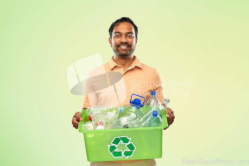 Image of smiling young indian man sorting plastic waste