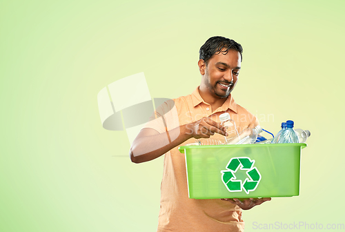 Image of smiling young indian man sorting plastic waste