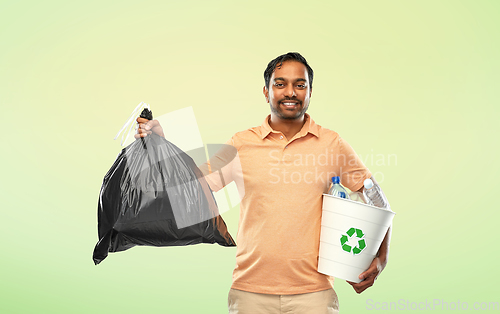 Image of smiling indian man sorting paper and plastic waste