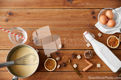 Image of pot with eggnog, ingredients and spices on wood