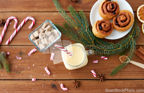 Image of eggnog with candy cane in mug and cinnamon buns