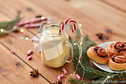 Image of eggnog with candy cane in mug and cinnamon buns