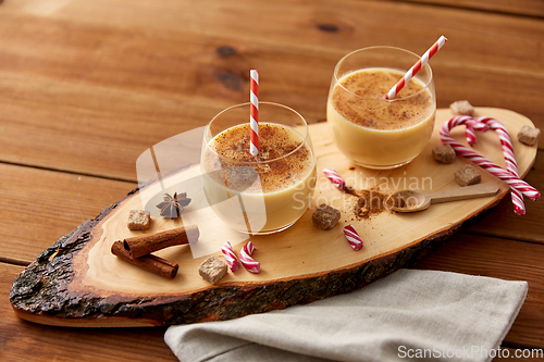 Image of glasses of eggnog, ingredients and spices on wood