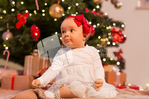 Image of baby girl at christmas tree with gifts at home