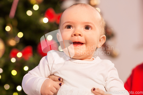 Image of smiling baby girl over christmas tree lights