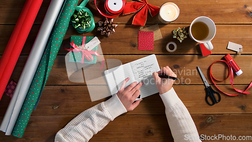 Image of hands writing to do list in notebook on christmas