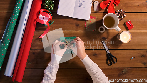 Image of hands packing christmas gift and attaching bow