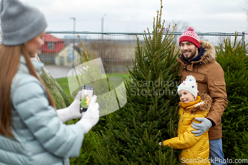 Image of family taking picture of christmas tree at market