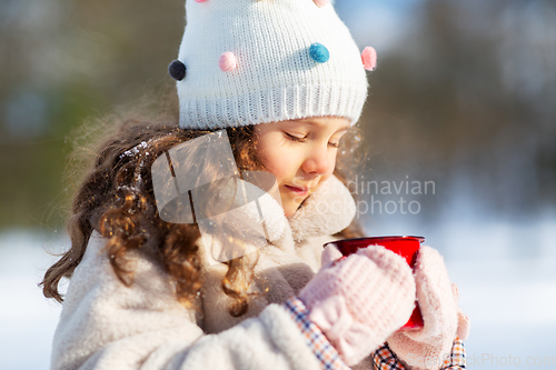 Image of little girl with cup of hot tea in winter park