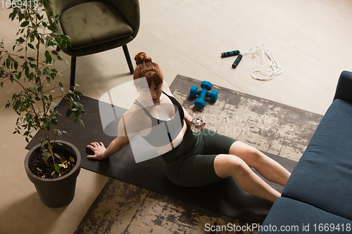 Image of Young woman exercising fitness, aerobic, yoga at home, sporty lifestyle. Getting active during lockdown, quarantine. Home gym.