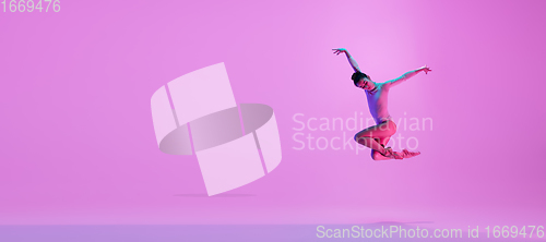Image of Young and graceful ballet dancer isolated on pink studio background in neon light. Art, motion, action, flexibility, inspiration concept.