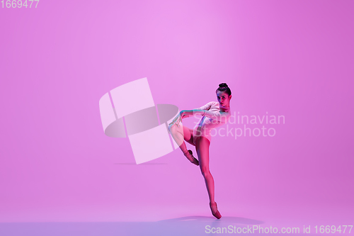 Image of Young and graceful ballet dancer isolated on pink studio background in neon light. Art, motion, action, flexibility, inspiration concept.