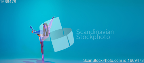 Image of Young and graceful ballet dancer isolated on blue studio background in neon light. Art, motion, action, flexibility, inspiration concept.